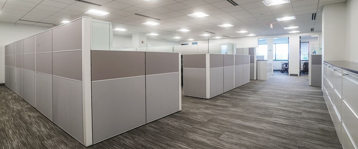 This image features a modern office layout with high cubicle partitions in a neutral color palette, providing a sense of privacy.