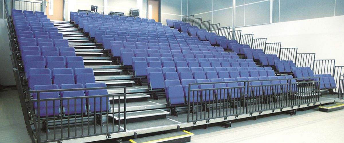 A set of telescopic gym bleachers with blue, injection-molded plastic seats.
