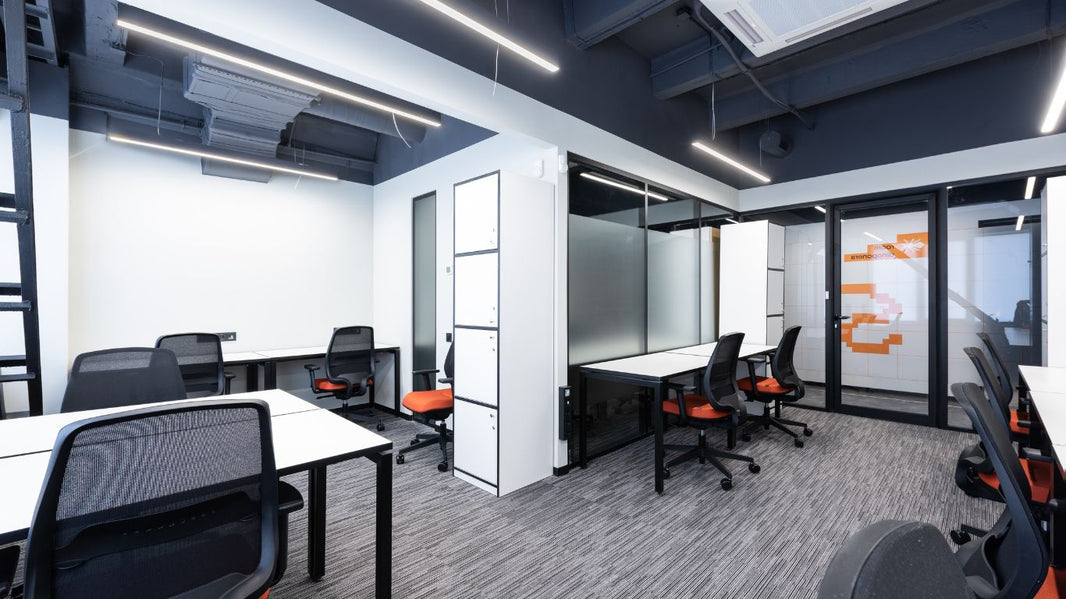 An ergonomic office chair with a black mesh backrest, black armrests, and an orange cushioned seat. The chair has a five-wheel base for mobility and adjustable height.