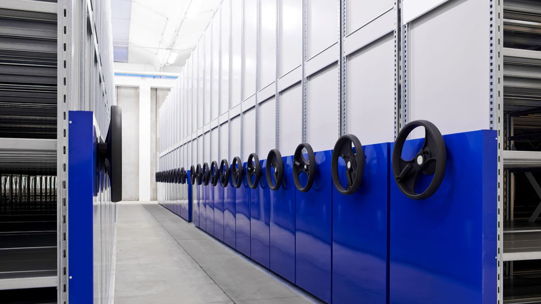 A long aisle between two rows of mobile shelving units in a storage facility.