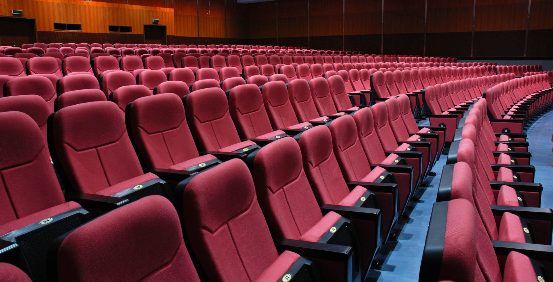 rows of cinema seats in red fabric with wood finish armrest